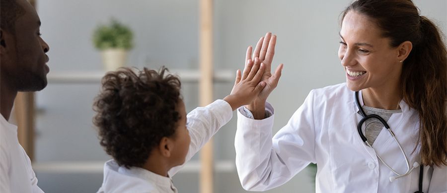 Full|Smiling female doctor giving a high-five to young child
