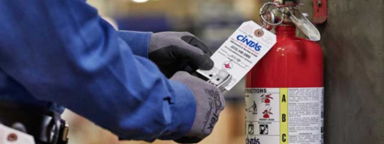 Cintas | Maintenance-worker-puching-tag-on-fire-extinguisher