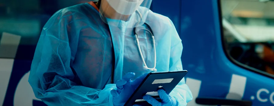 Wide | Mobile Health Services Partners - Healthcare Worker Using Digital Tablet Outside Mobile Clinic
