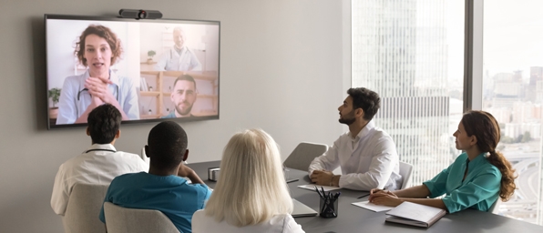 Full|Five people in a conference room collaborating with a remote employee