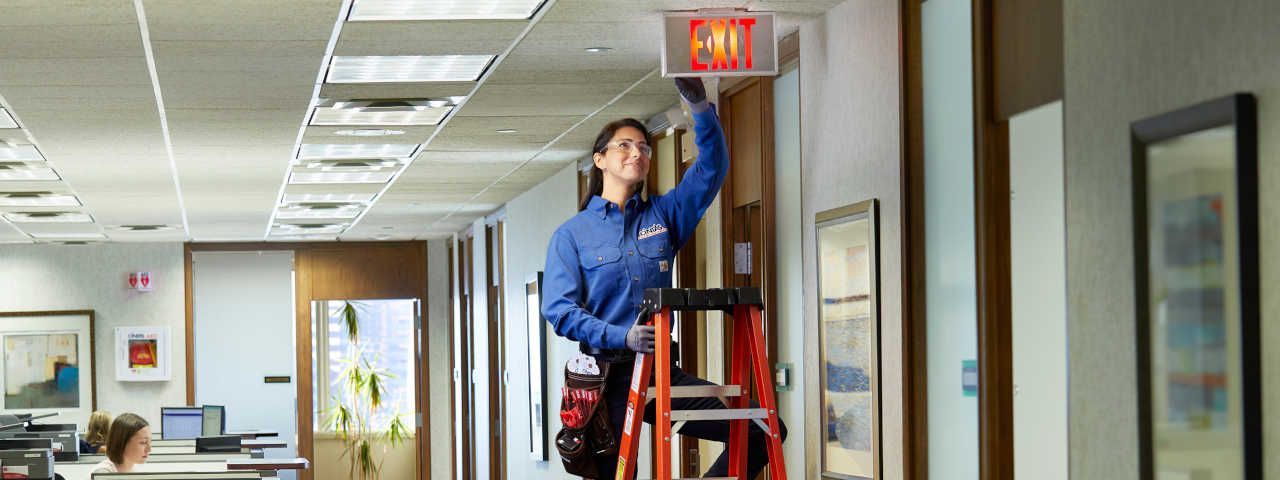 Cintas | Maintenance-worker-on-exit-sign
