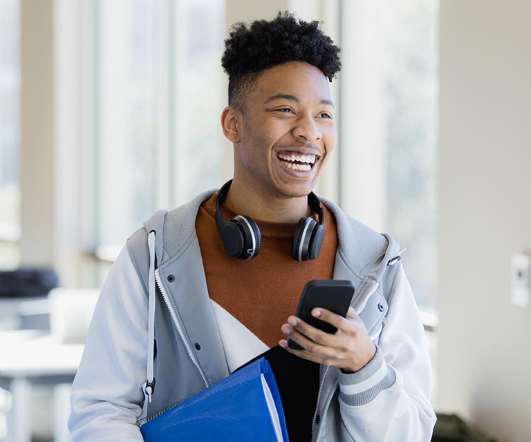 Sqre|Laughing student wearing headphones around his neck