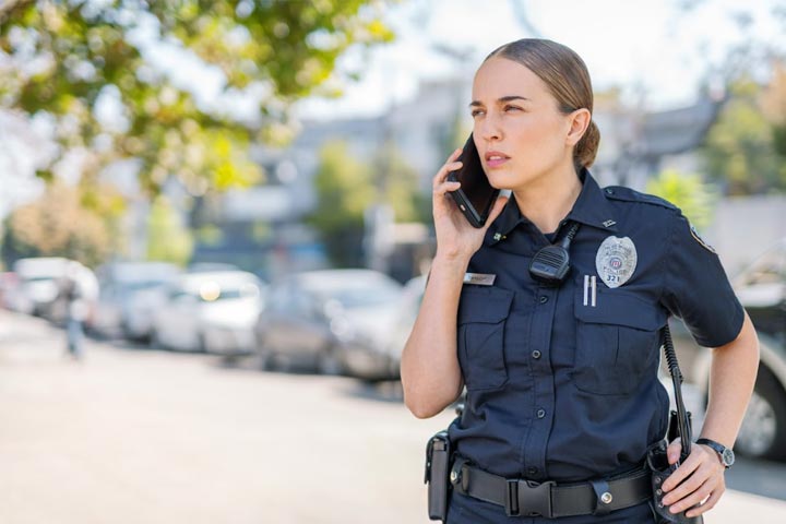 Tile|Female police officer standing outside talking on phone