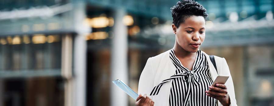 Woman walking outside and looking at her phone.